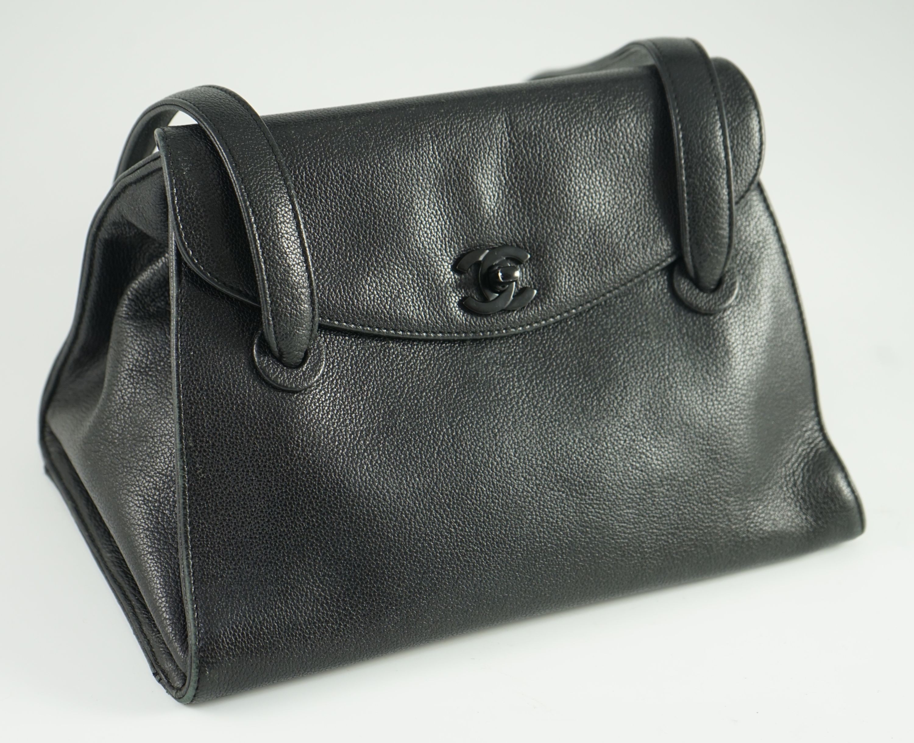 A black Chanel shoulder bag with two straps and Chanel logo lock